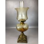 Amber coloured glass oil lamp on square brass base with original chimney, approx 66cm tall