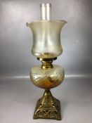 Amber coloured glass oil lamp on square brass base with original chimney, approx 66cm tall