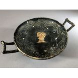 Greek pottery Kylix with remains of black glaze bearing figure of a man's head, twin handles,