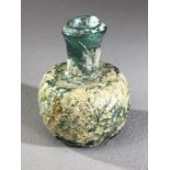 Small glass oil / perfume bottle, possibly Roman, in green glass with patches of iridescence and