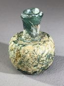 Small glass oil / perfume bottle, possibly Roman, in green glass with patches of iridescence and