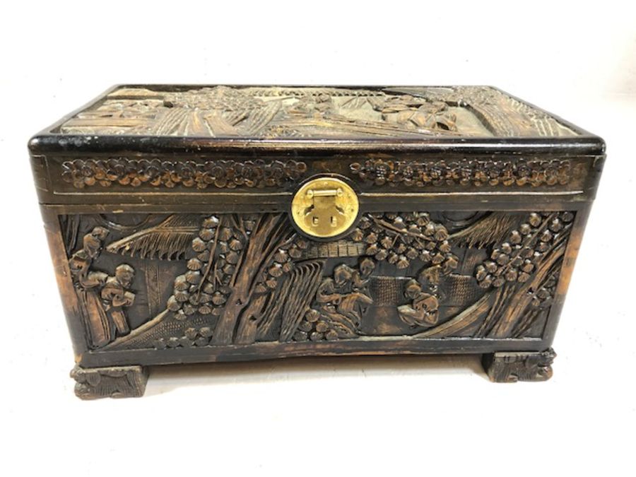 Small heavily carved Chinese camphor wood chest with brass fittings on square carved feet, approx