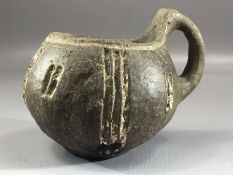 Small clay single handled drinking vessel / cup with remnants of white decoration and carved