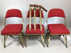 Set of three interlocking, folding theatre chairs with red upholstered seats and backs, total length