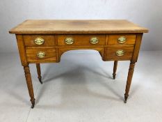 Antique kneehole writing desk on turned legs with original castors, five drawers and brass