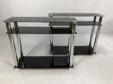 Pair of modern black glass and chrome shelving units, each approx 90cm x 30cm x 76cm tall