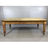 Large antique pine dining table with baluster turned legs on castors and with single drawer to one
