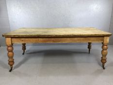 Large antique pine dining table with baluster turned legs on castors and with single drawer to one