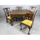 Carved wooden extendable table with bow legs and rose detailing, accompanied by four ornately carved