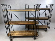Pair of industrial style shelving units, on castors, each made up of three wooden shelves in metal