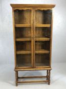 Glass fronted two door bookshelf / display cabinet raised on turned legs, approx 91cm x 30cm x 187cm