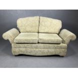 Cream upholstered drop arm two seater sofa on castors