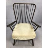 Ercol model 1913 armchair with large wingback spindle back and shaped armrests, raised on short