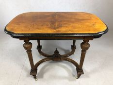 Ebonised and veneered occasional table with curved X-shaped stretcher on turned legs with castors,