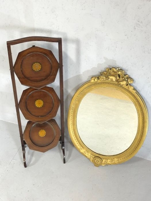 Gilt framed oval mirror and a three tier inlaid folding cake stand