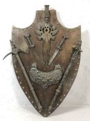 Metal mace, axe and knives, mounted on a wooden shield, approx 78cm x 50cm