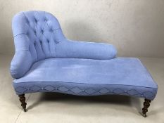 Modern chaise lounge in blue linen, with turned legs on castors, stitching detail and buttons (