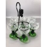 Set of six vintage wine glasses with green stems and etched grape design suspended on metal stand