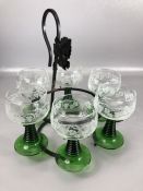 Set of six vintage wine glasses with green stems and etched grape design suspended on metal stand