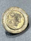 Artefact: Circular bronze brooch depicting the head of a man, approx 24mm in diameter