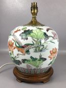 Oriental ceramic lamp base depicting lotus flowers, dragonflies and birds, on wooden stand, approx