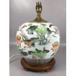 Oriental ceramic lamp base depicting lotus flowers, dragonflies and birds, on wooden stand, approx