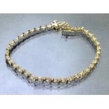 9ct Gold tennis bracelet set with diamonds in flower shaped settings and divided 'S' shaped Gold