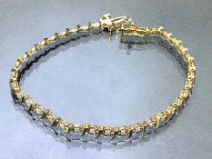 9ct Gold tennis bracelet set with diamonds in flower shaped settings and divided 'S' shaped Gold