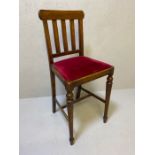 Tall antique wooden chair with turned front legs, slatted back and velvet upholstered seat