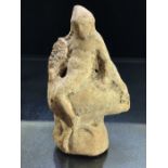 Terracotta pipe clay figurine, possibly Roman, depicting a youth seated backwards, on the back of