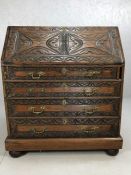 Heavily carved bureau with flight of four drawers and fall front opening to reveal pigeon holes,