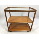 Mid Century style teak trolley, possibly Danish, with two shelves and glass top, on castors,