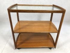 Mid Century style teak trolley, possibly Danish, with two shelves and glass top, on castors,