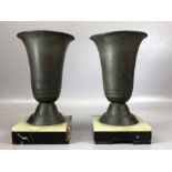 Pair of metal vases on marble plinths, each approx 21cm tall