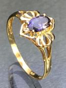 9ct Gold ring set with a faceted Amethyst flanked by two small diamonds and with pierced Gold