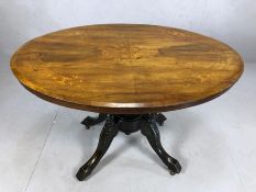 Victorian oval tilt top table with decorative inlay on carved legs with original castors, approx