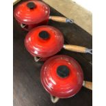 Collection of three Le Creuset cast iron lidded saucepans in red
