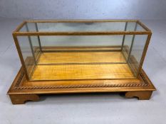 Glass display case on wooden base with carved rope twist detailing, base approx 70cm x 32cm x 18cm