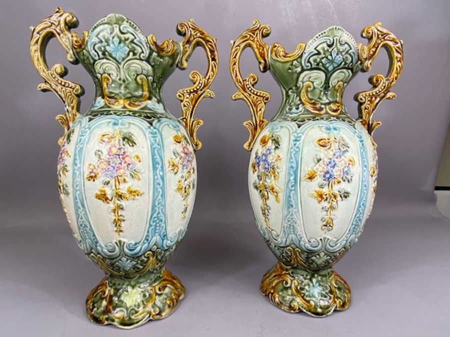 Pair of majolica twin handled urns, each approx 35cm tall