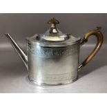 Silver teapot with embossed detailing and wooden handle and finial. Underside of lid has hallmarks