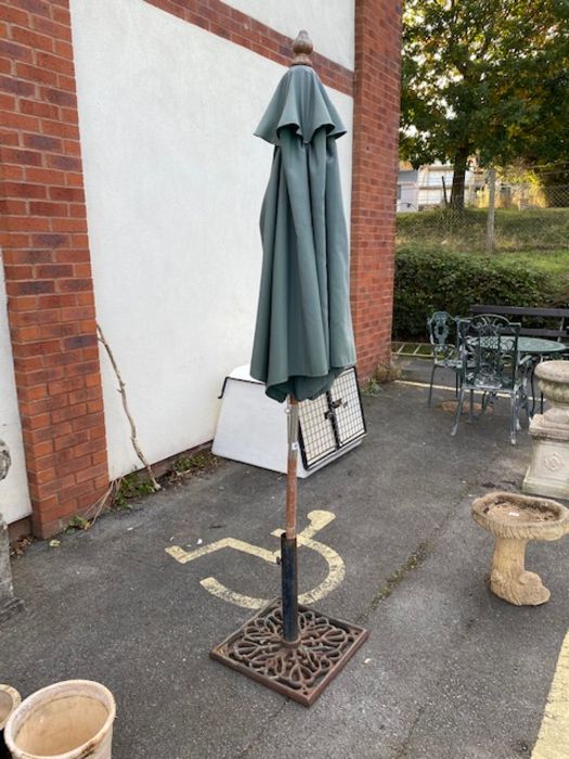 Wrought iron umbrella stand and green fabric parasol
