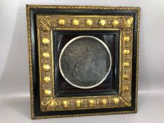 Framed metal, possibly bronze, circular plaque depicting woman holding a lit torch surrounded by