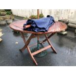 Circular teak garden table and parasol with wrought iron base, table approx 120cm in diameter