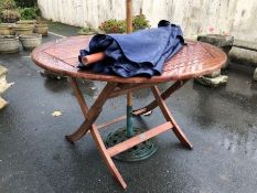 Circular teak garden table and parasol with wrought iron base, table approx 120cm in diameter