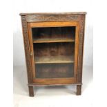 Antique display cabinet with single glazed door, two shelves, heavily carved border and fine inlay