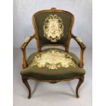 Carved wooden framed and tapestry upholstered armchair with floral detailing on curved legs,