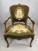 Carved wooden framed and tapestry upholstered armchair with floral detailing on curved legs,