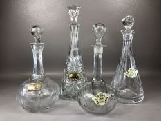 Four cut glass decanters each with metal label, two silver and two enamel tin