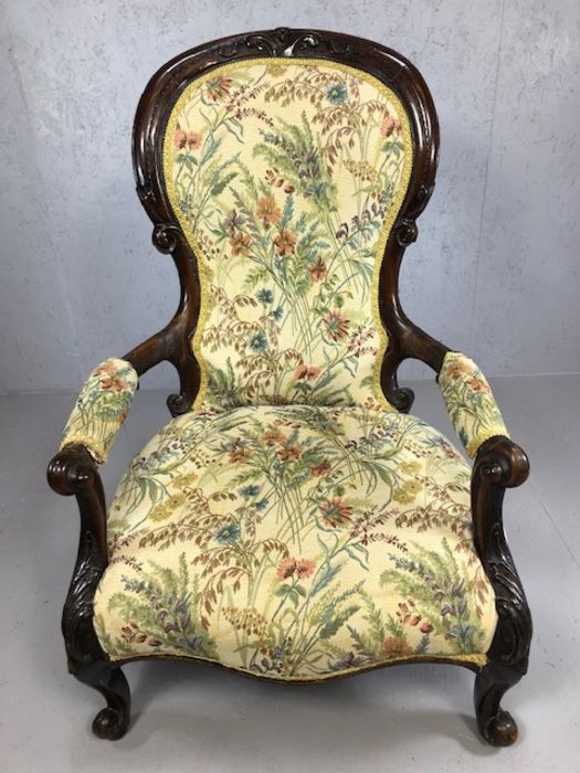 Heavily carved wooden framed low armchair, with floral fabric upholstery, approx 97cm tall