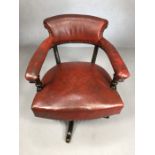 Antique red leather captain's chair on swivel base with stud detailing